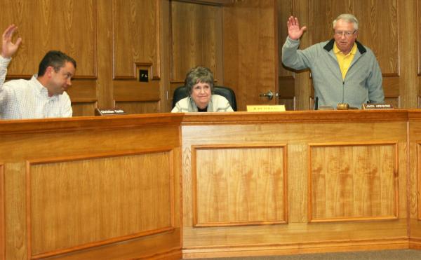 Gazette photo/LYNDA STRINGER PISD Board President Jack Arnwine, right, and Board Member Christian Yantis, left, raise their hands to vote in favor of accepting PISD Superintendent Judy Pollan's decision to retire while Pollan looks on. Article Image Alt Text