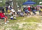 Juneteenth celebrators gather in tents and under trees, barbecuing, playing cards, listening to music, enjoying the company